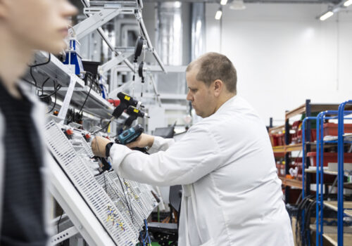 A person assembling an electrical system in a factory